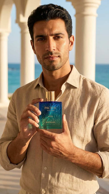 A man in a beige linen shirt holds a Pacific Blue Kenzo fragrance bottle in front of a sunny outdoor background with white columns and the ocean.
