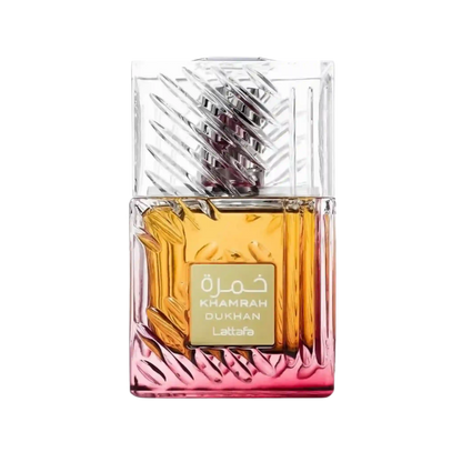 A rectangular glass perfume bottle with a faceted clear cap and a gold label reading 'KHAMRAH DUKHAN' and 'Lattaafa'. The bottle contains amber-gold liquid and transitions to a pink tint at the bottom, shown on a plain white background.