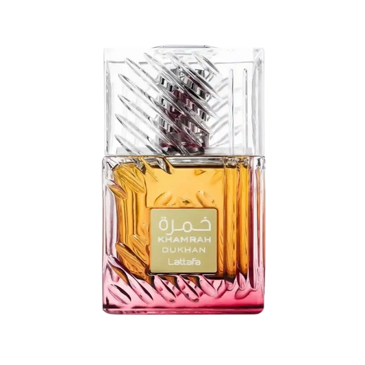 A rectangular glass perfume bottle with a faceted clear cap and a gold label reading 'KHAMRAH DUKHAN' and 'Lattaafa'. The bottle contains amber-gold liquid and transitions to a pink tint at the bottom, shown on a plain white background.