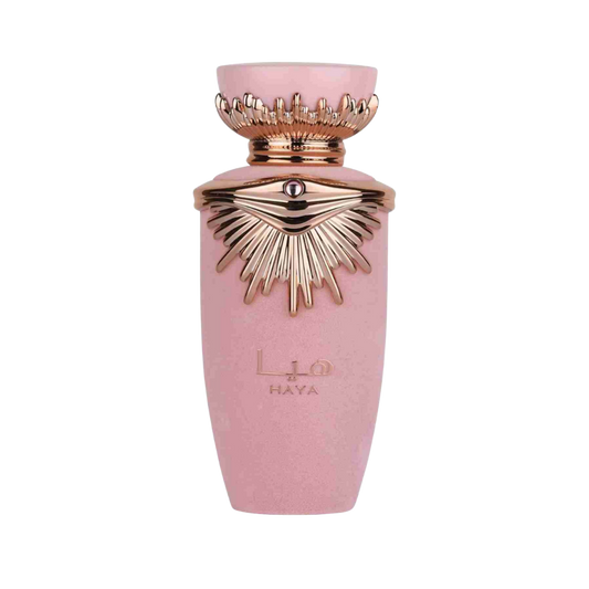 A pink cylindrical perfume bottle with a metallic rose gold crown cap and sunburst emblem on the front, featuring the brand name HAYA.