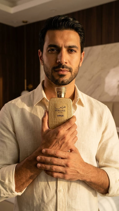 A man in a cream linen shirt holds a textured beige bottle of Viper Italian Vodka with a gold cap against a warm-toned indoor background.